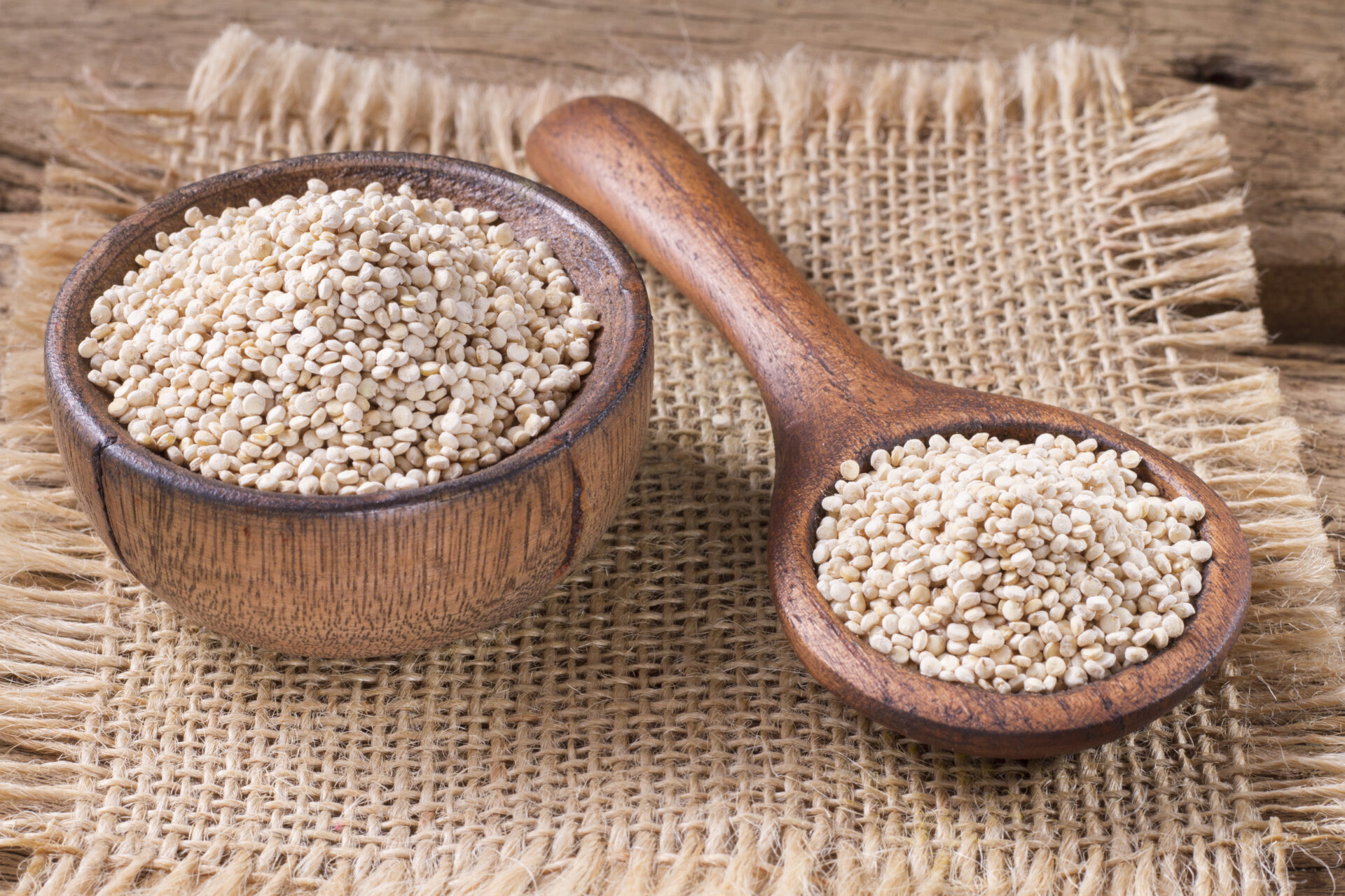 Quinoa seeds in bowl on rustic wood.